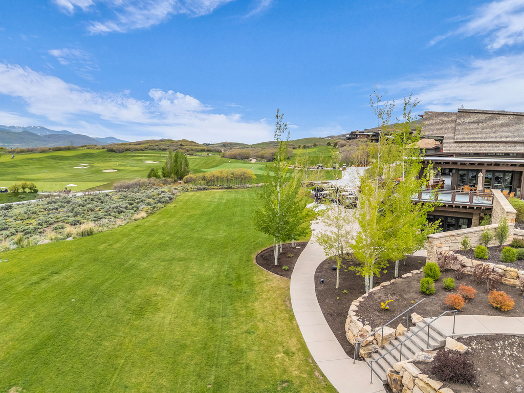 Expansive green space and golf course setting with a multi-level structure featuring exterior patios and natural stone landscaping