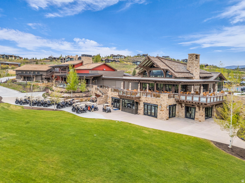 Expansive clubhouse with stone and wood siding, featuring multiple balconies, a prominent stone chimney, and a large manicured lawn