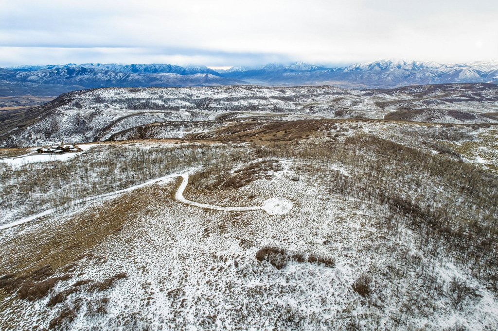 Expansive, snow-dusted landscape featuring distant mountain ranges and a winding access road