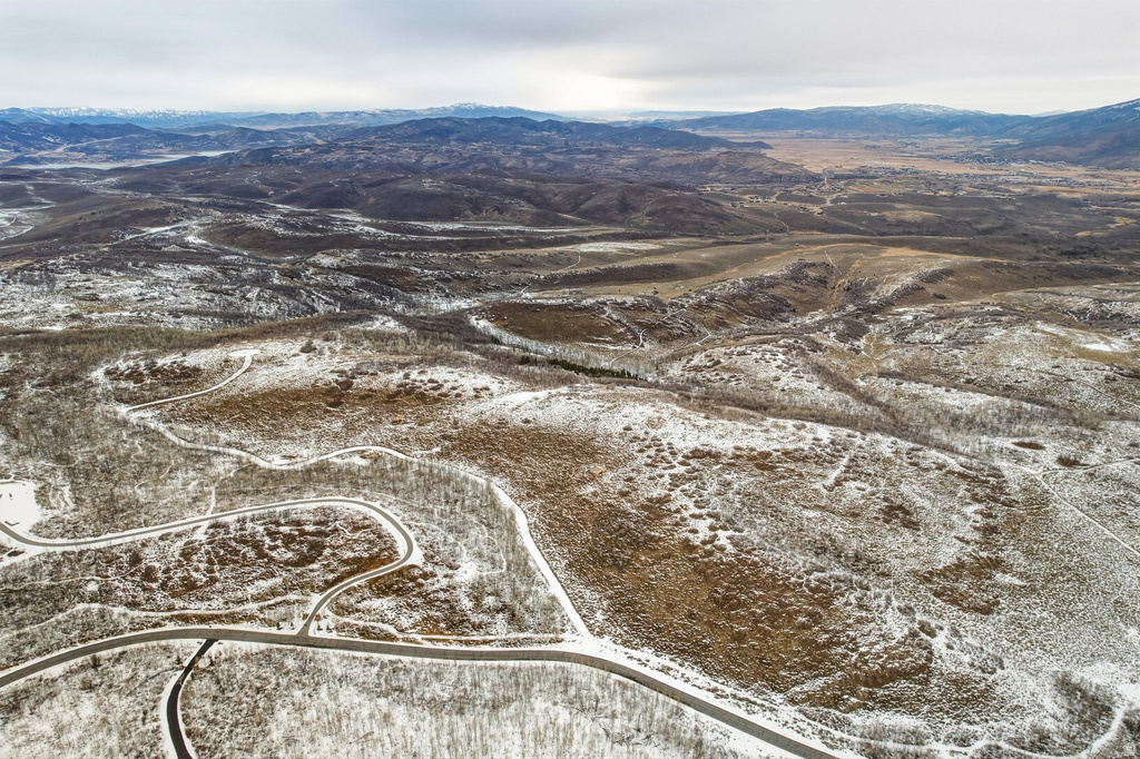 Expansive mountain terrain featuring snow-dusted hillsides and distant mountain ranges