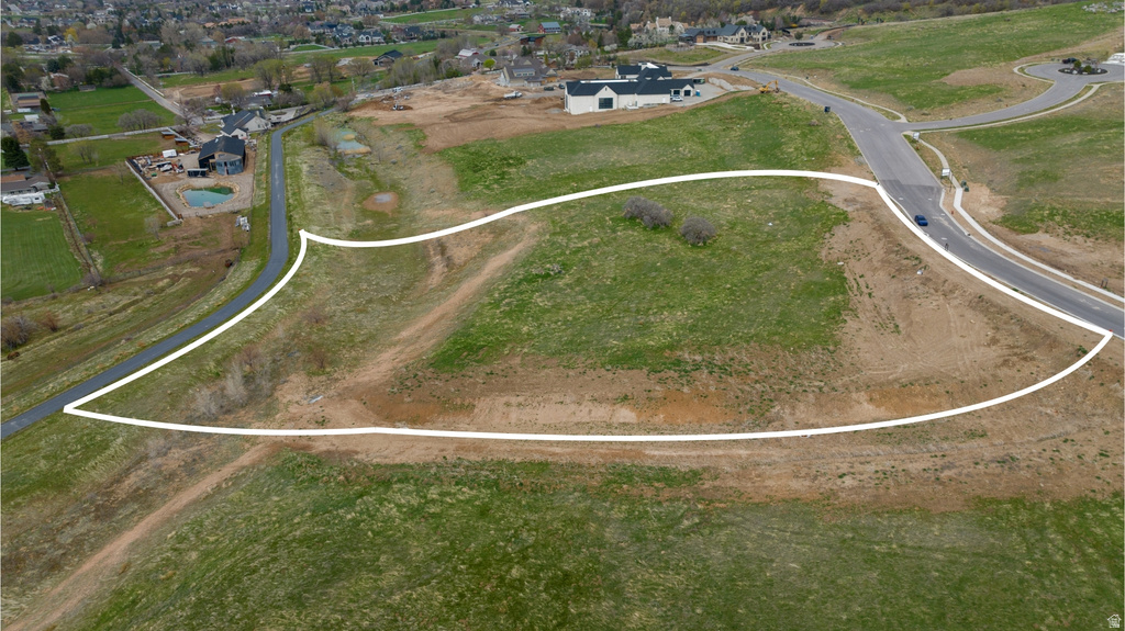 Expansive undeveloped parcel featuring a gentle slope, established roadway access, and a natural grass landscape