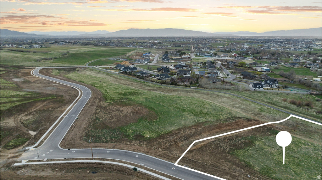 Expansive undeveloped parcel featuring a curved asphalt road frontage with integrated sidewalks
