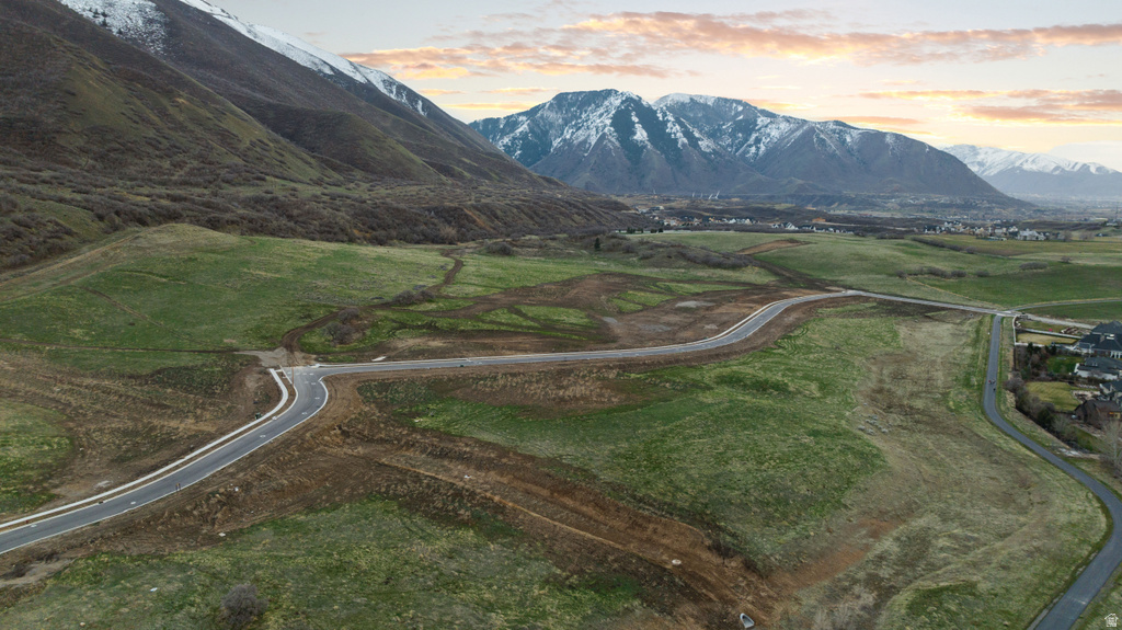 Expansive undeveloped land featuring paved roads, mountainous backdrop, and established residential areas in the distance
