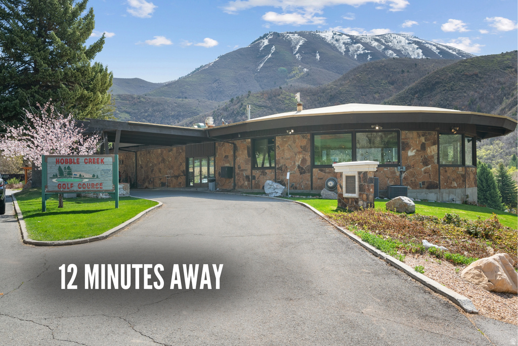 Circular architectural design featuring stone facade, extensive windows, and a paved driveway