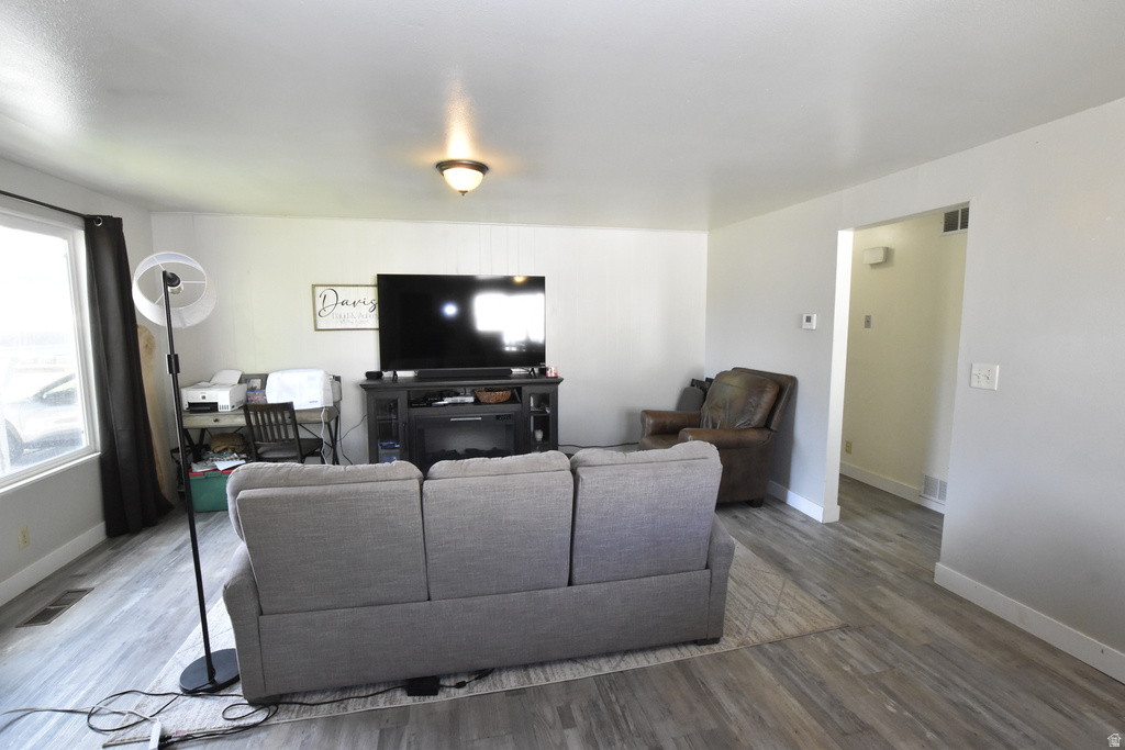Spacious interior room featuring wood-finish flooring, light-toned walls, a large window, and an overhead light fixture