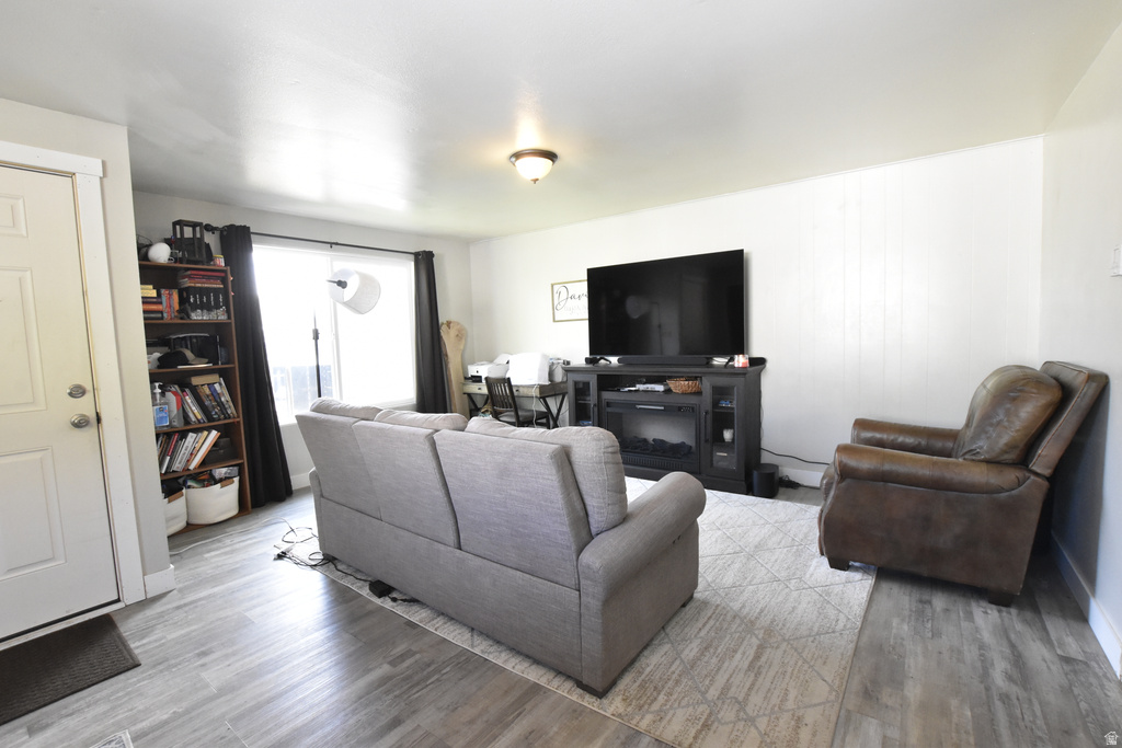 Bright living area featuring wood-finish flooring, white walls, and a recessed window with dark curtains