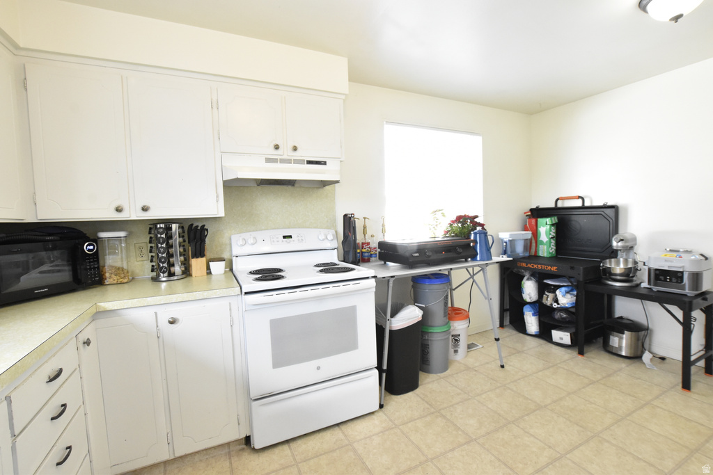 Kitchen featuring white cabinetry with brushed nickel hardware, white range, and a window providing natural light
