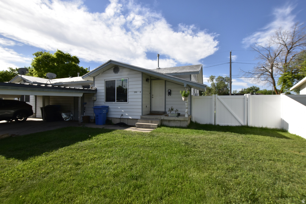Single-story residence featuring white siding, a covered carport, and a white privacy fence