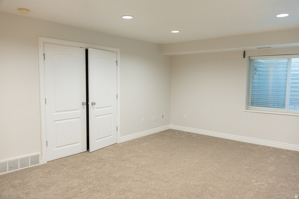 Neutral tone wall paint, recessed lighting, double doors with arched panels, window with blinds, and carpet flooring
