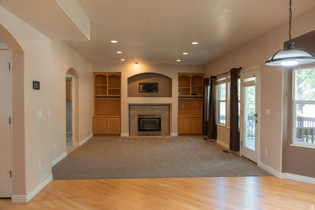 Wood-finish flooring, recessed lighting, arched doorways, a stone-clad fireplace, and built-in cabinetry enhance this space