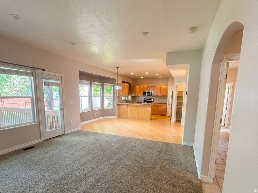 Spacious interior featuring a carpeted living area, wood-finish flooring, and a kitchen with warm wood cabinetry