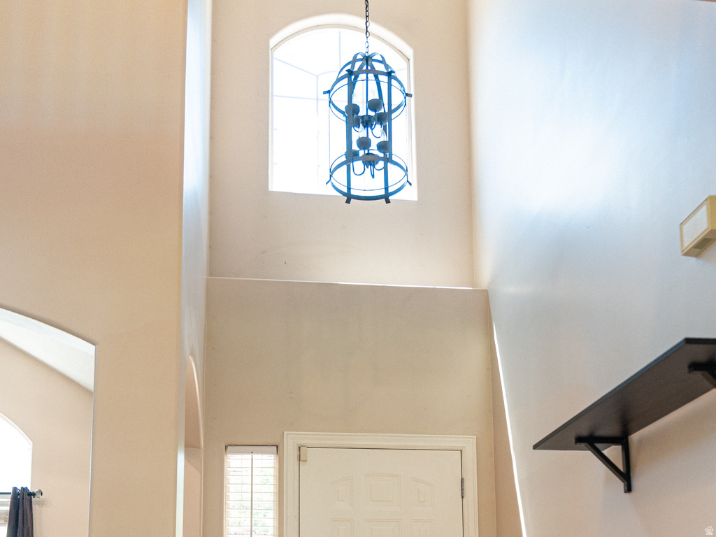 Entryway featuring a white paneled door, light wood-finish flooring, and a two-story ceiling with an arched window