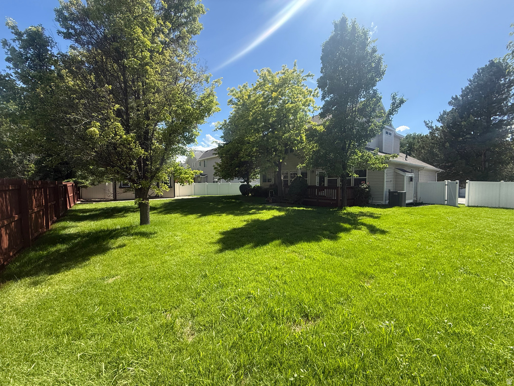 Expansive backyard featuring a manicured lawn, established trees, and a combination of wood and vinyl fencing