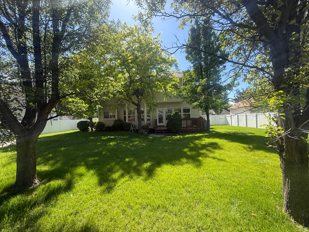 Expansive rear yard featuring mature trees, a broad lawn, and a light-colored privacy fence