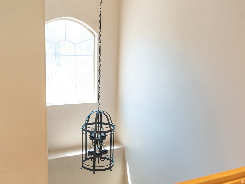 Two-story foyer featuring a decorative caged chandelier, arched window, and natural wood handrail