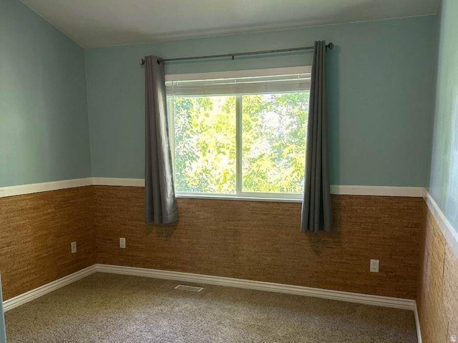 Room featuring carpet flooring, a window with exterior views, and a ceiling fan with integrated lighting