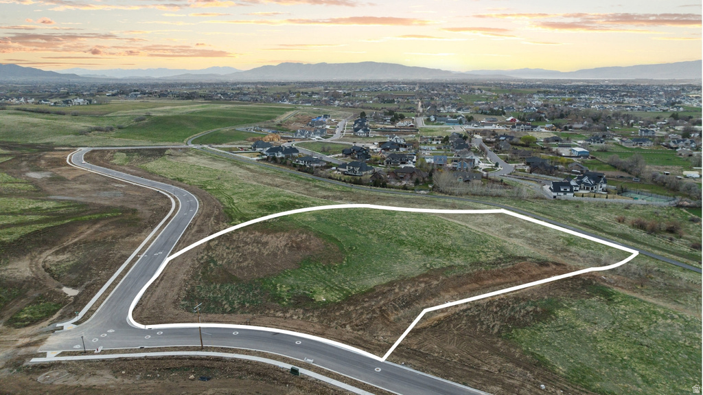 Expansive lot with a grassed area and partial road frontage, framed by a distant mountain range