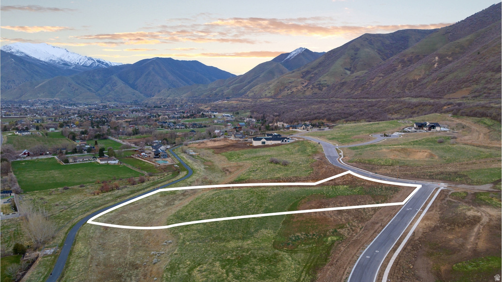Expansive land parcel featuring a paved road, mountain backdrop, and varying terrain