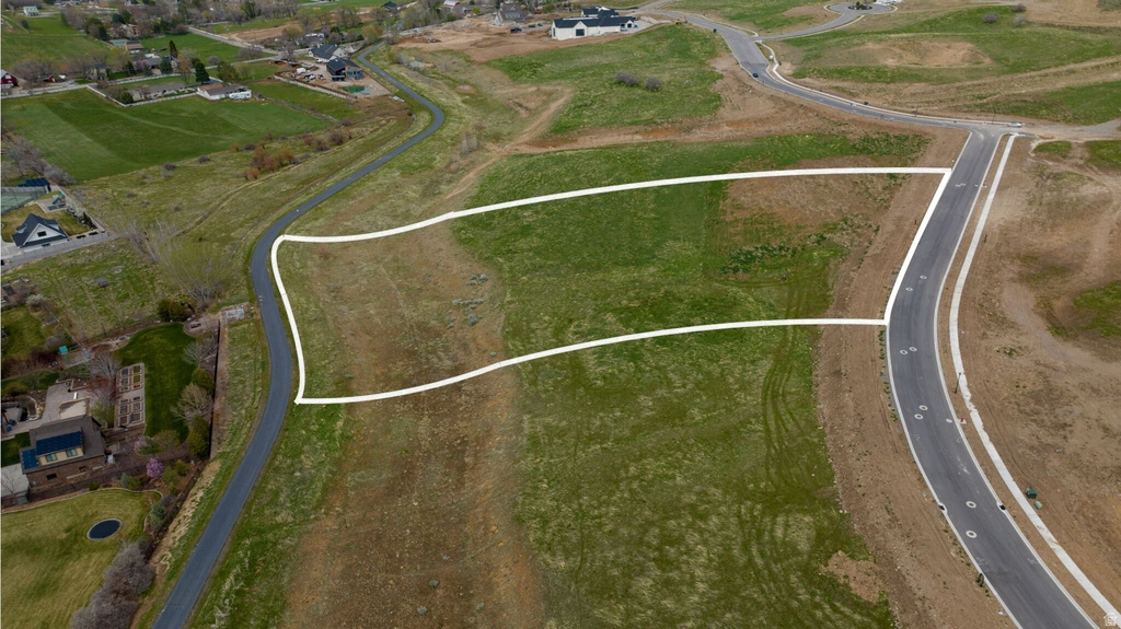 Expansive undeveloped land parcel featuring a paved road frontage, established curb cuts, and surrounding green space