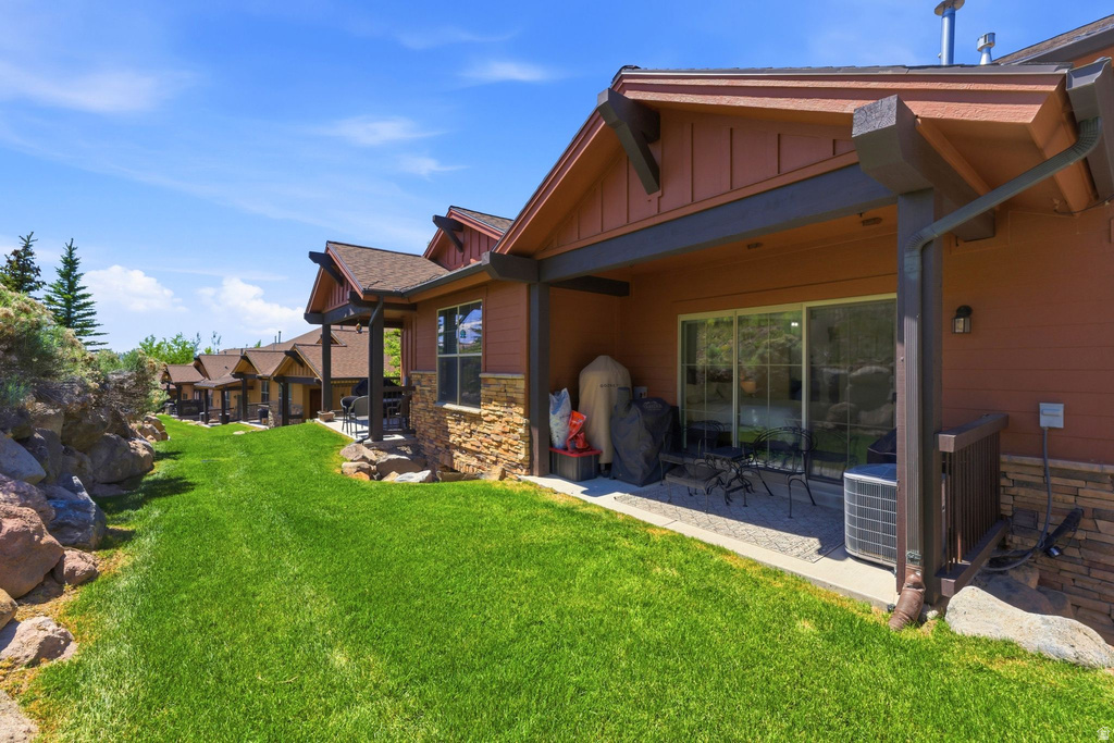 Rear exterior featuring a sliding glass door, an outdoor patio, and a manicured lawn