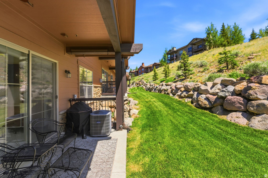 Covered patio with a concrete surface, featuring a sliding glass door and an exterior wall light fixture