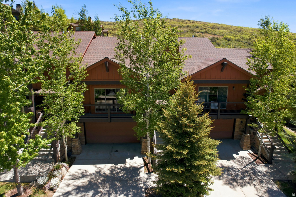 Terraced residence featuring a brown siding exterior, a brown shingle roof, and multiple balconies