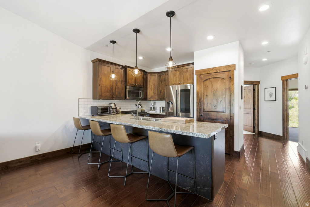 Kitchen featuring wood-finish flooring, recessed lighting, and a breakfast bar with pendant lighting