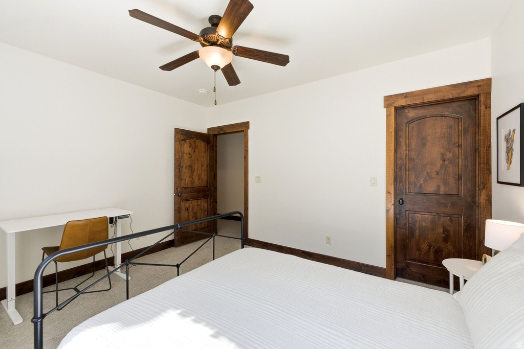 Bedroom featuring a ceiling fan with integrated lighting, wood-finish interior doors with dark hardware, and coordinating wood-finish trim