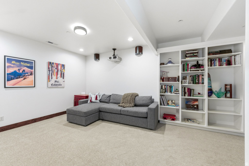 Spacious room featuring neutral carpet flooring, recessed lighting, and a full-wall built-in bookcase