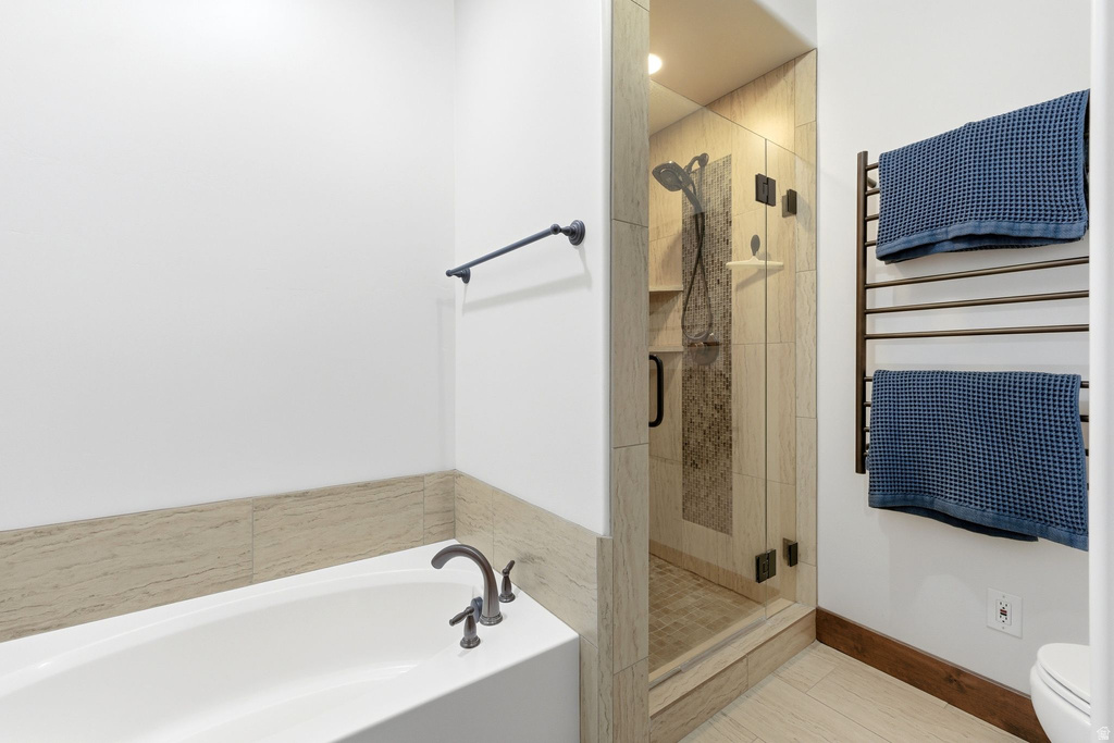Bathroom featuring a glass-enclosed shower with a tiled surround, a separate bathtub with dark-finished fixtures, and a wall-mounted towel warmer