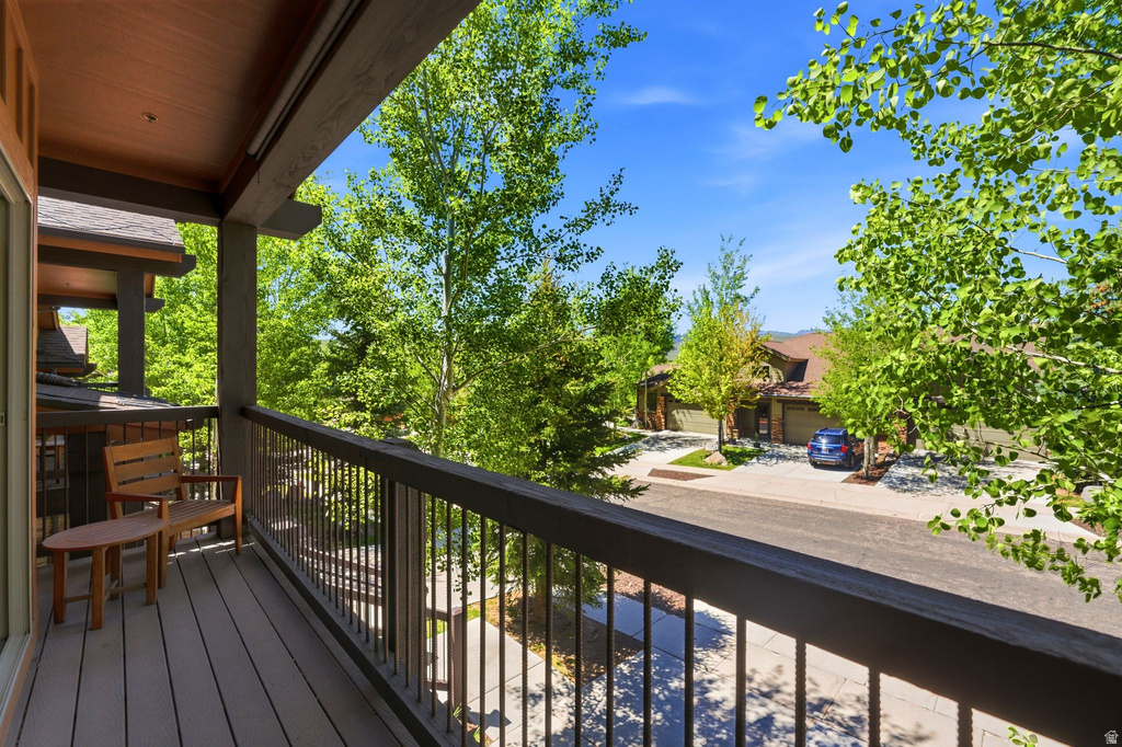 Covered balcony featuring wood-finish decking, dark wood railings with metal spindles, and a wood-paneled ceiling
