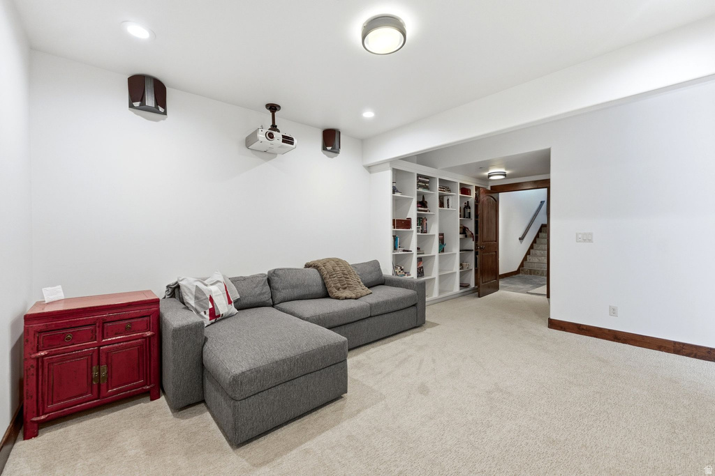 Dedicated media space featuring a ceiling-mounted projector, integrated speakers, recessed lighting, and built-in shelving