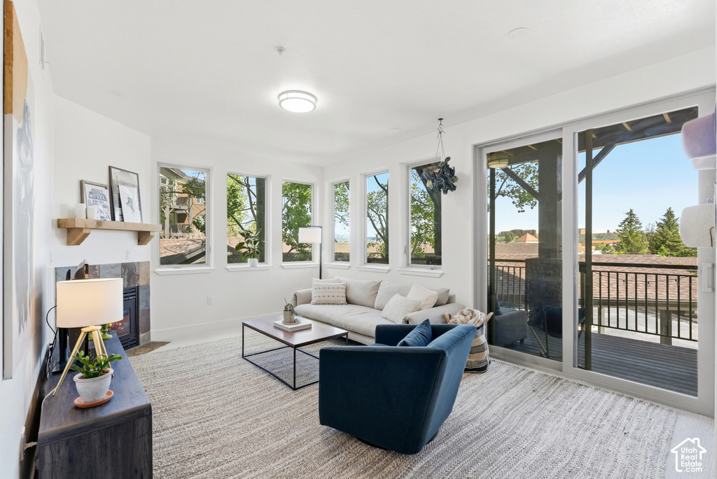 Living area featuring multiple windows, a built-in fireplace with a stone surround and wood mantle, and sliding glass doors opening to an exterior deck with railing