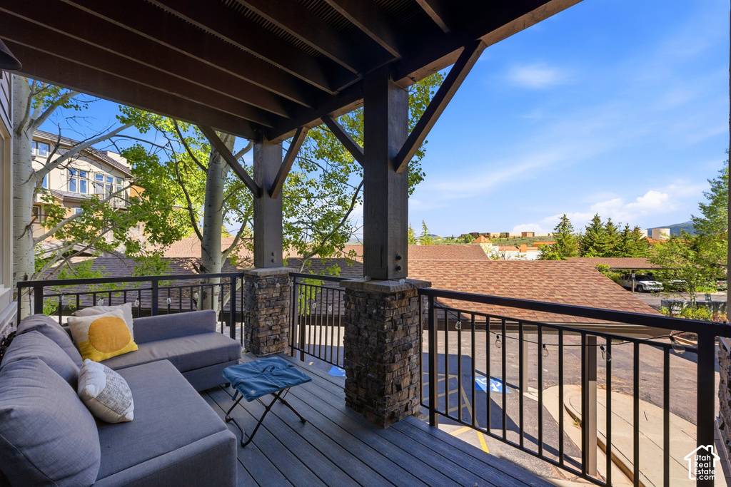 Covered outdoor balcony featuring a wood-finish ceiling, stone-clad pillars, and a black metal railing