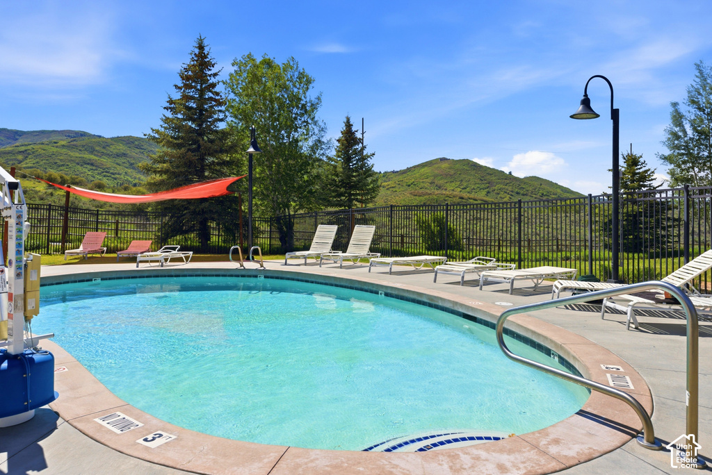 Outdoor swimming pool with concrete decking, surrounded by a black metal fence