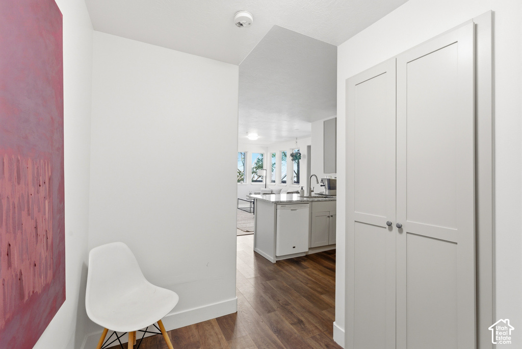 Interior hallway featuring wood-finish flooring, white walls, and built-in white shaker-style cabinetry with circular hardware