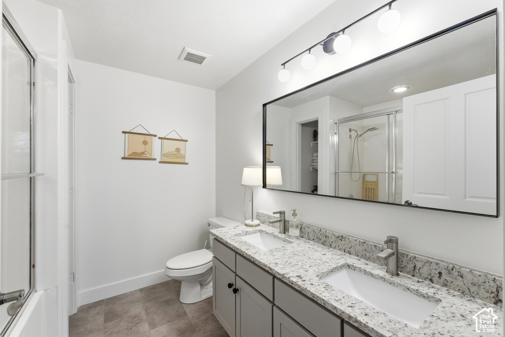 Bathroom featuring a double vanity with stone countertops, undermount sinks, and grey cabinetry