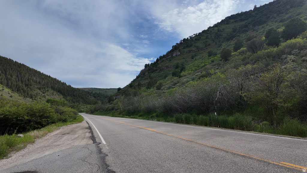 Paved road traversing a natural landscape with verdant hillsides and distant mountains