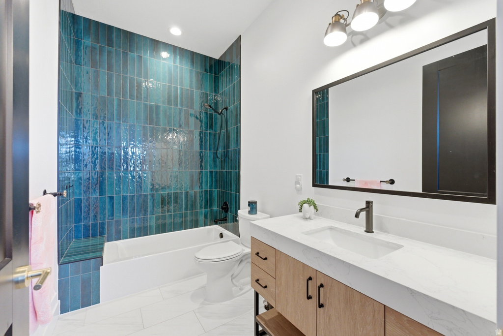 Bathroom featuring a deep blue vertical tile shower surround, integrated bathtub, and white floor tiling