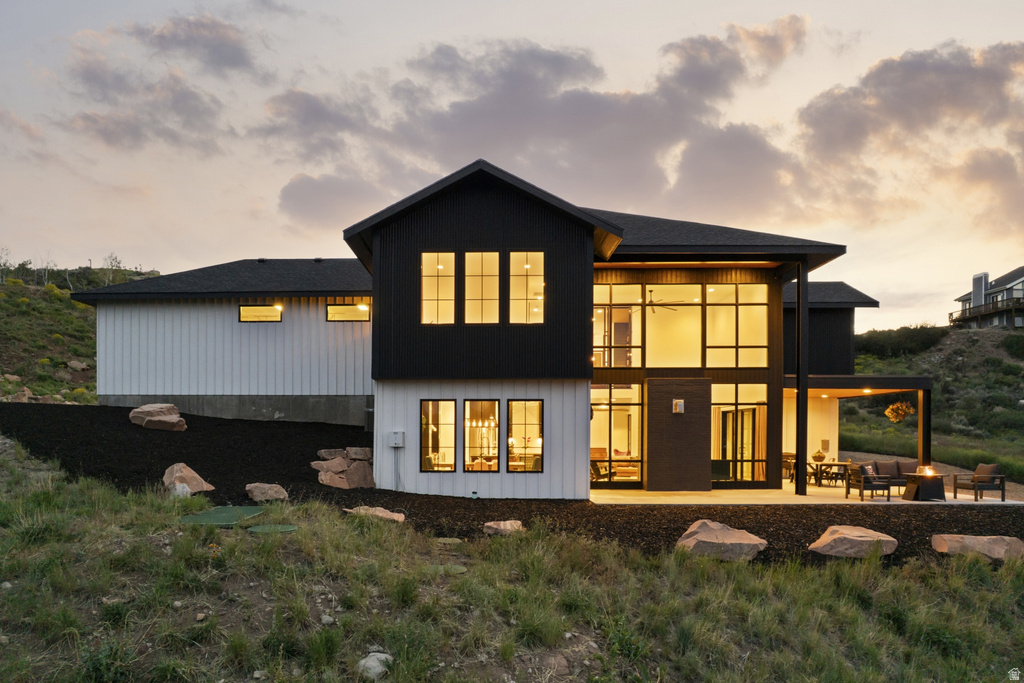 Contemporary exterior featuring a black and white facade with extensive window walls, an outdoor patio with a covered section, and natural rock landscaping