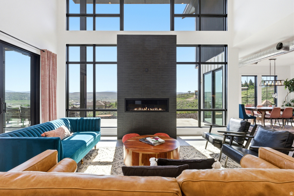 Two-story living area featuring a full-height black brick fireplace with a linear gas insert, expansive black-framed windows, high ceilings, and light-toned flooring