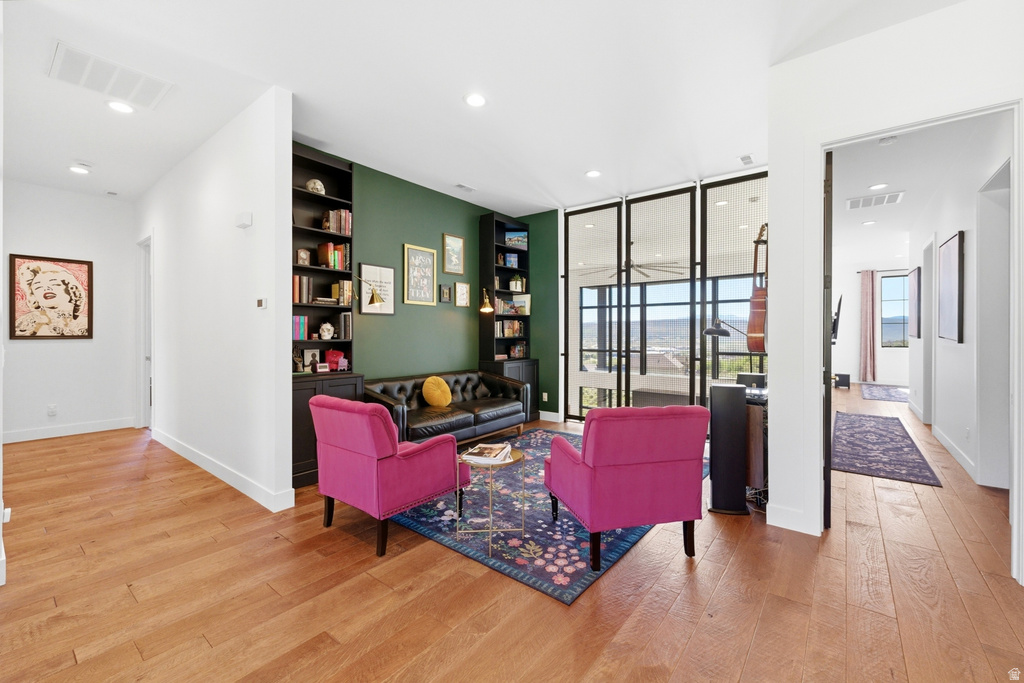 Open-concept living area with wood-finish flooring, recessed lighting, and a feature wall with built-in shelving