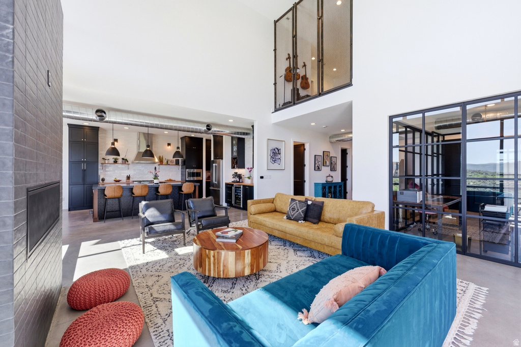 Open-concept living space featuring high ceilings, a fireplace with dark tile surround, and expansive window walls