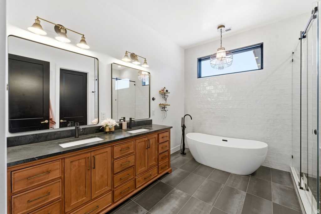Spacious bathroom featuring a dual vanity with wood cabinetry, dark countertops, and undermount sinks