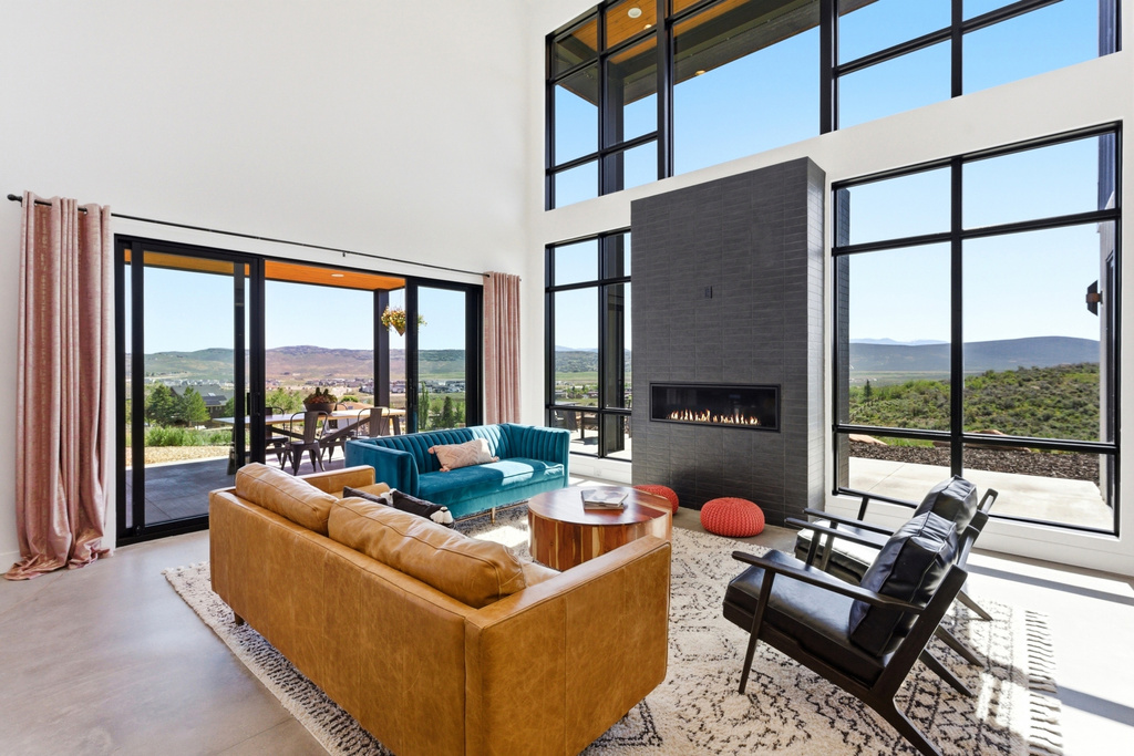 Double-height living space featuring expansive windows, a sleek linear fireplace with dark tile surround, and polished concrete flooring