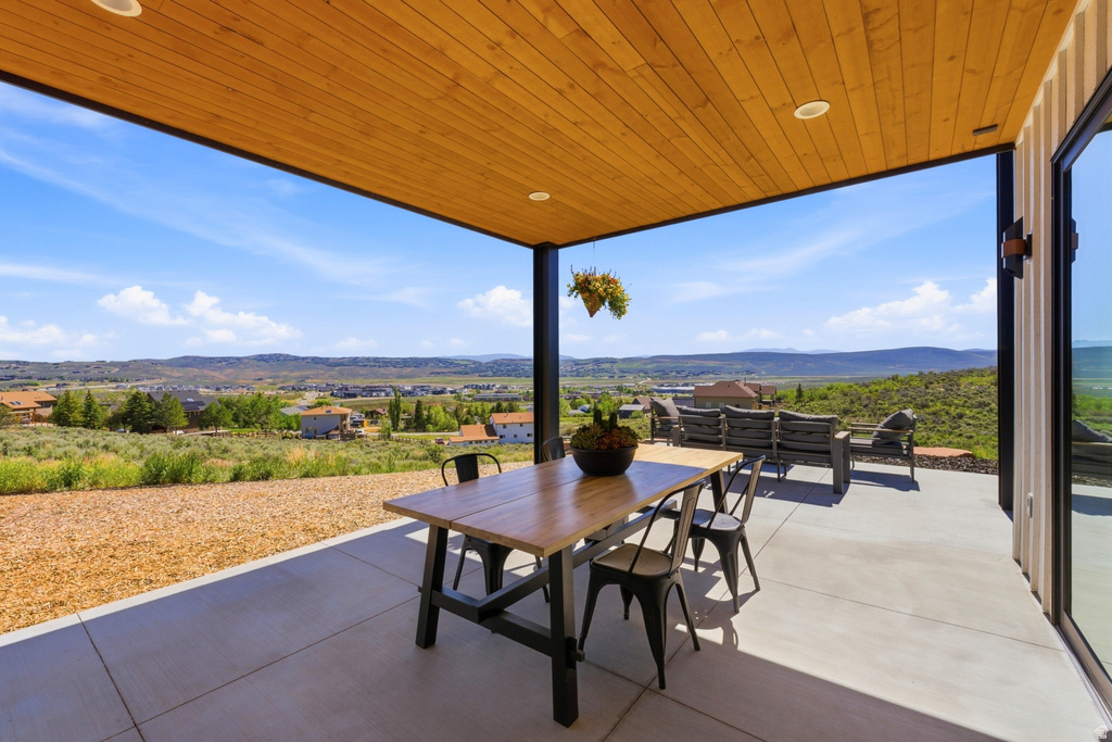 Covered outdoor patio featuring a wood-finish plank ceiling with recessed lighting, an expansive concrete surface, and a large sliding glass door