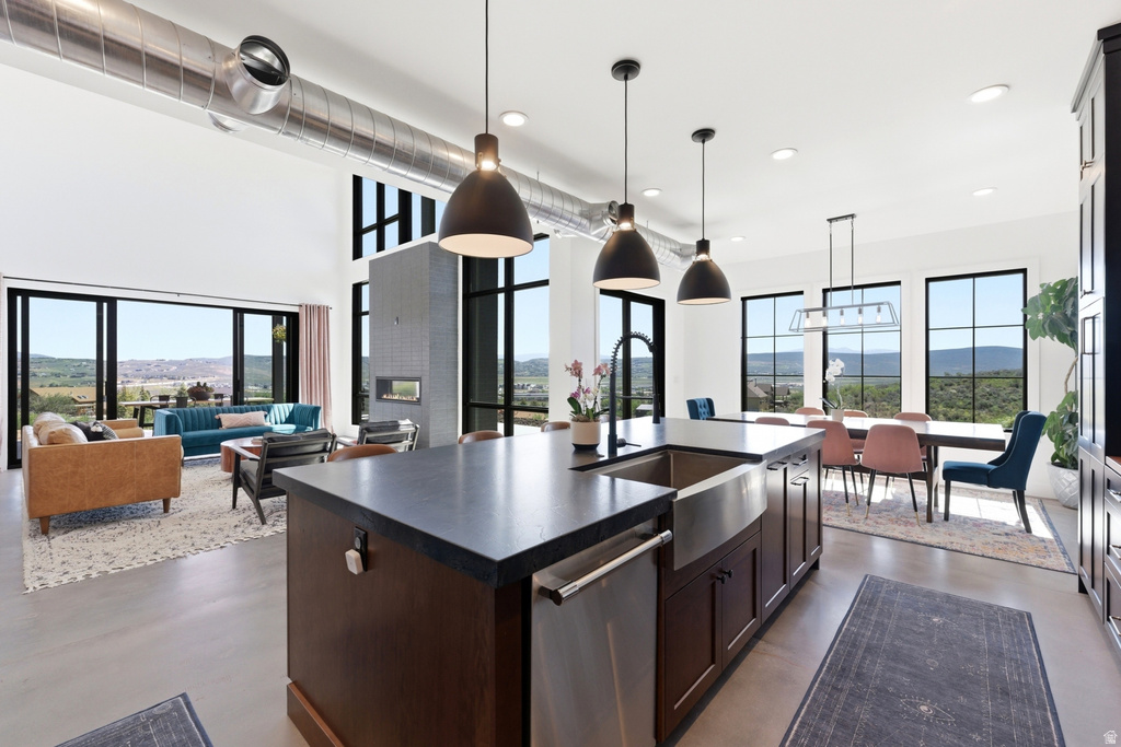 Spacious kitchen island with an undermount farmhouse sink, dark cabinetry, and black pendant lighting