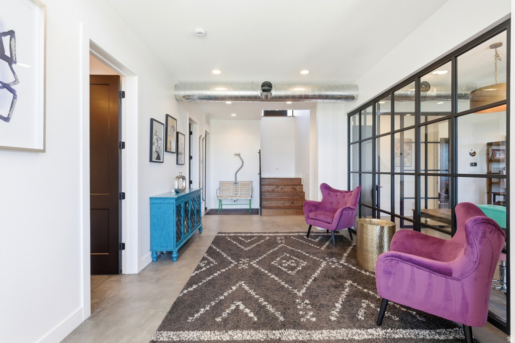 Interior hallway featuring an exposed industrial-style duct, dark wood-finish doors, and a transparent room divider with black framing