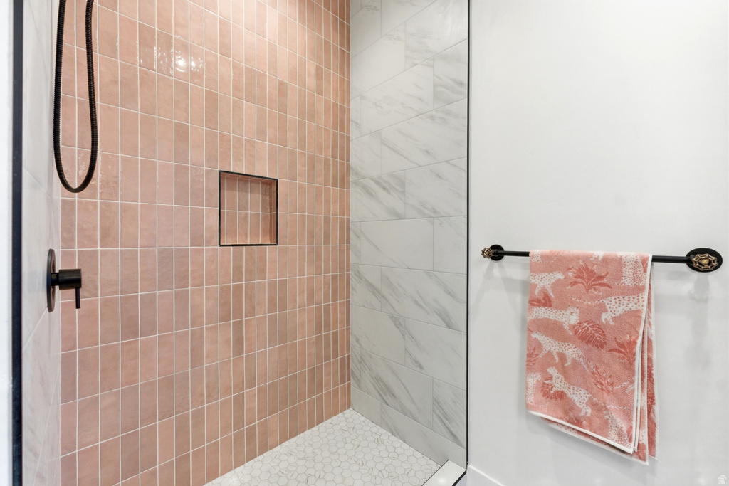 Shower enclosure featuring vertical pink subway tile, black matte fixtures, a recessed shower niche, and white hexagonal floor tiles