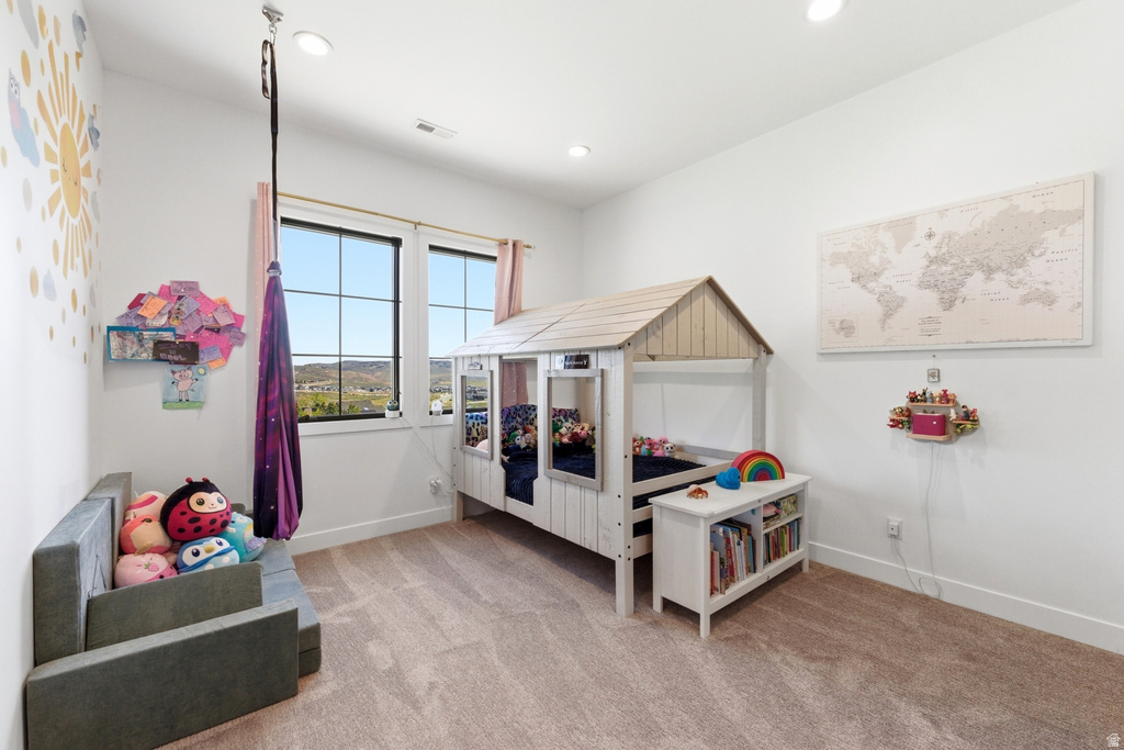 Spacious room featuring broad windows with dark framing, recessed ceiling lighting, and light-toned carpeting